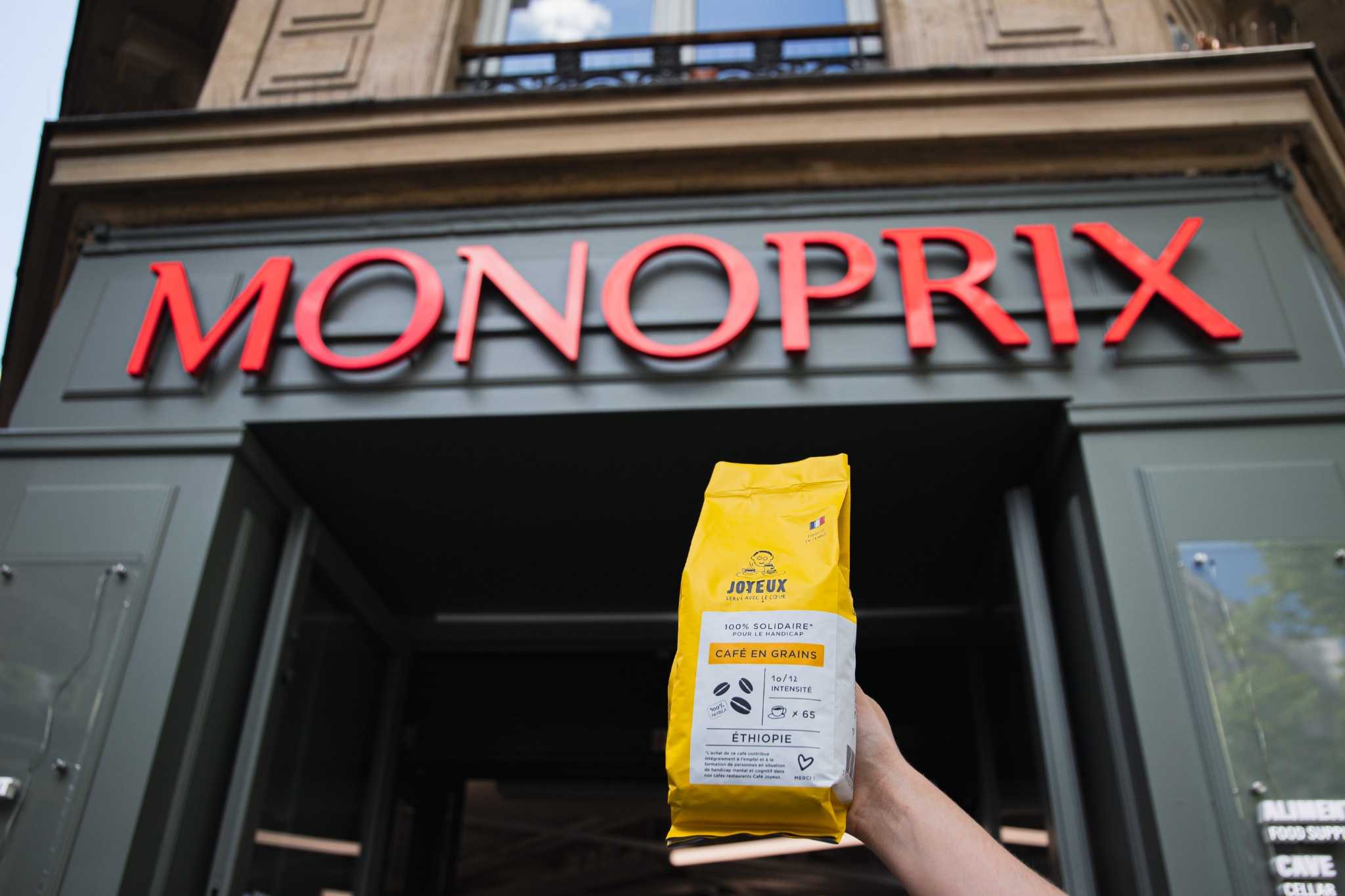 Sachet de café en grains Café Joyeux devant l'enseigne Monoprix